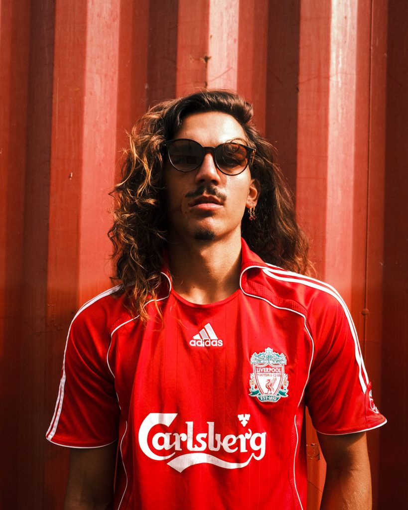 man with sunglasses on, wearing a red vintage football jersey.
