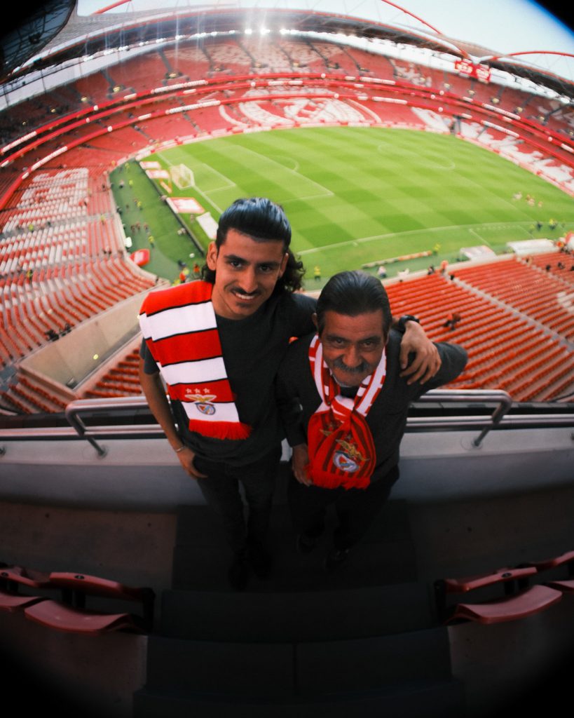 two men wearing scarves in an empty football stadium.