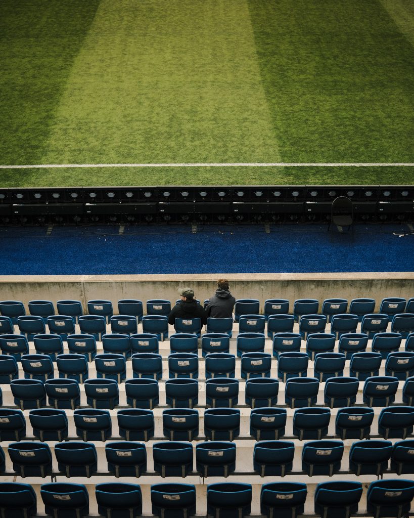 Two men sitting alone in a football stadium.